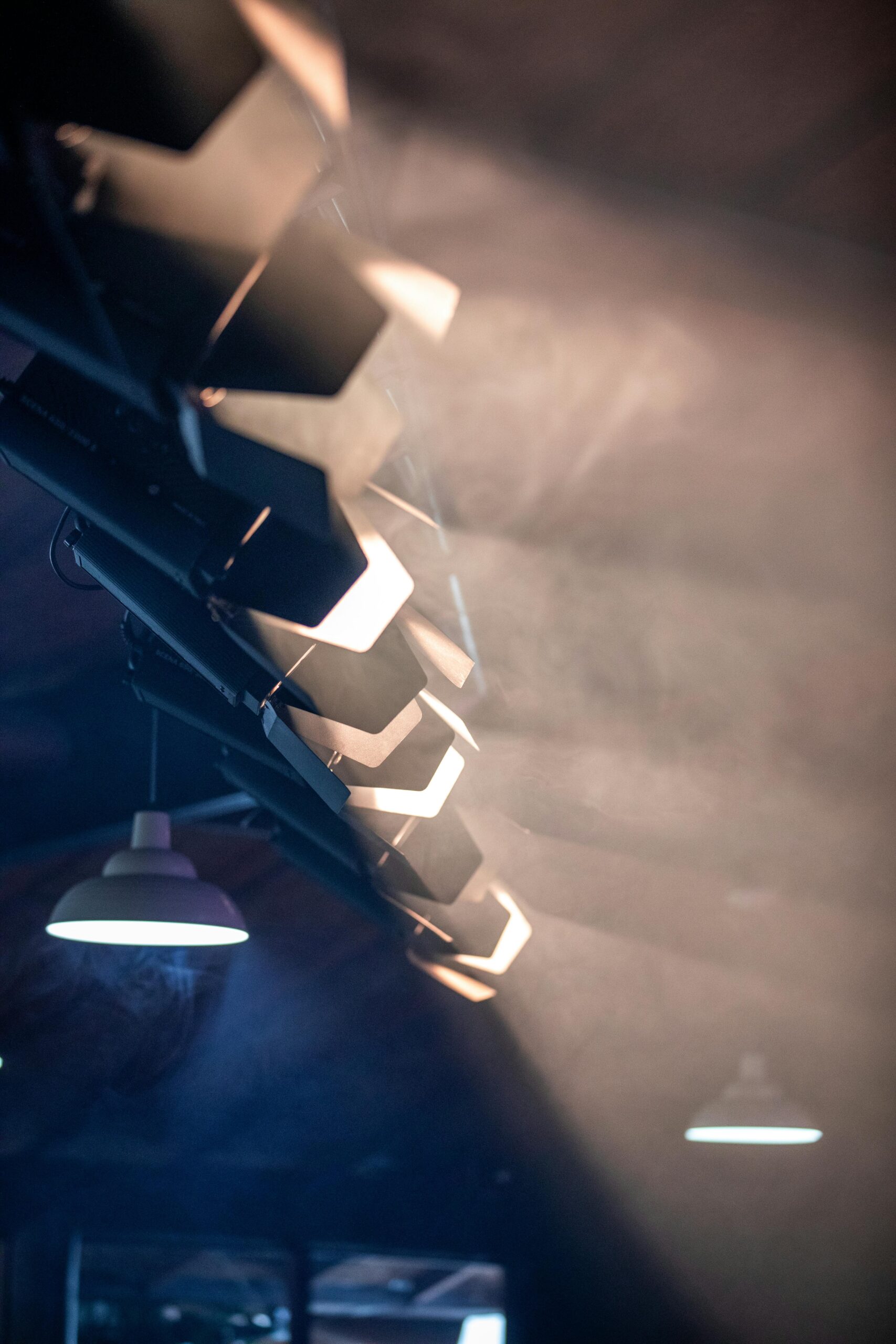 Close-up of bright stage spotlights emitting haze and glare at a live event, representing the sensory challenges of harsh lighting for neurodivergent attendees