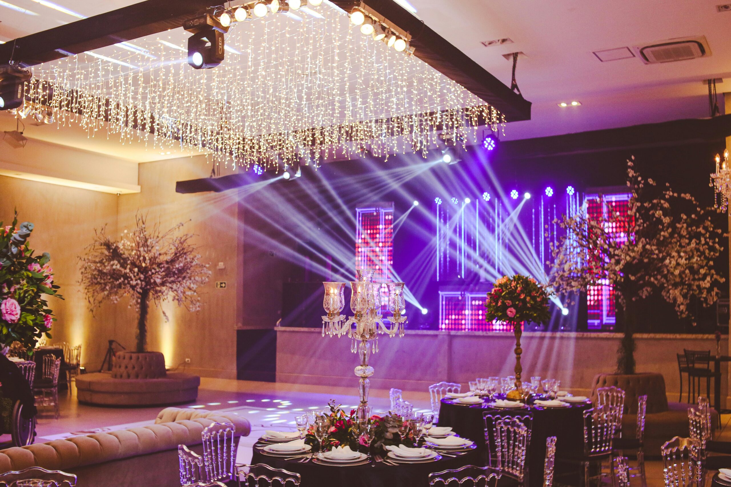 A glamorous event venue with bright stage lighting, crystal chandeliers, and elaborate table settings — illustrating high-stimulation environments that benefit from sensory-inclusive event design